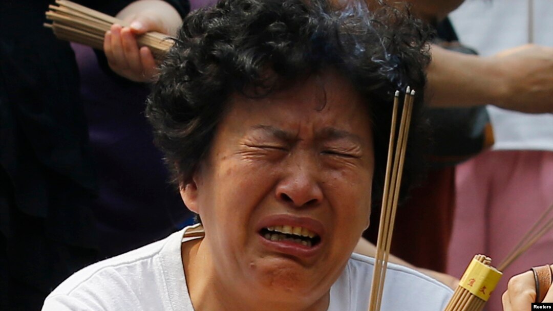 A family member of a passenger aboard the missing Malaysia Airlines flight MH370 cries as she burns incense to pray at Yonghegong Lama Temple in Beijing, June 15, 2014. 