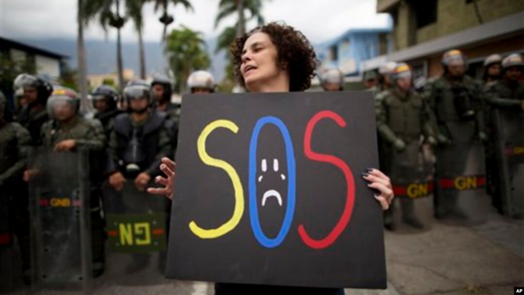 Una manifestante sostiene un cartel durante protestas frente a la fuertemente custodiada embajada cubana en Caracas.