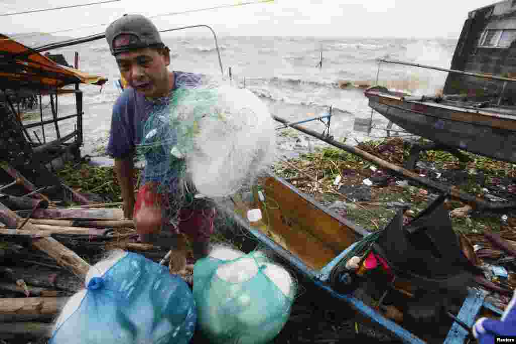 A fisherman carries his net after making it safely back to shore in the fishing village after a strong winds from Typhoon Haiyan battered Bayog town in Los Banos, Laguna city, south of Manila, Nov. 8, 2013. 