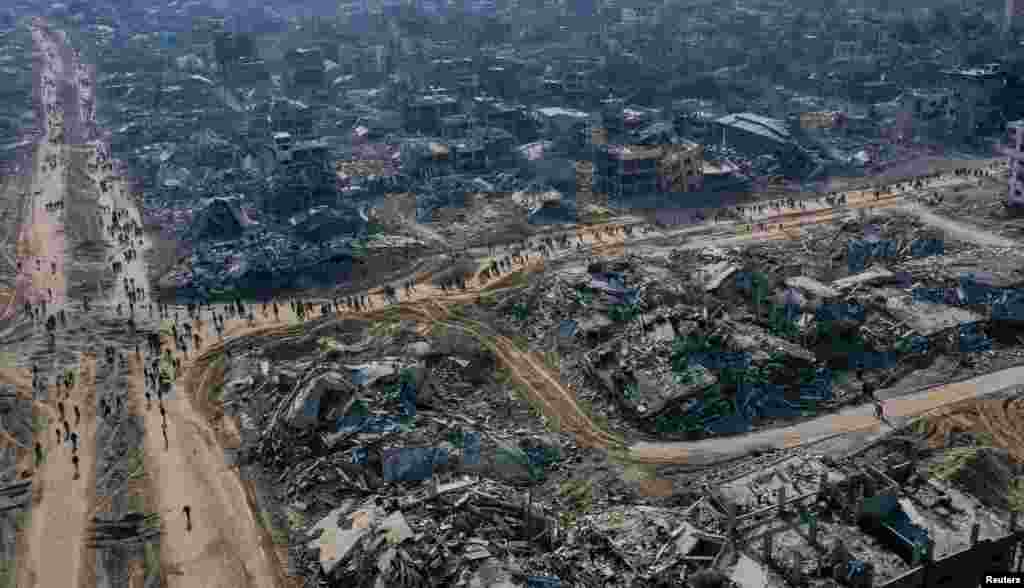 A drone view shows displaced Palestinians walking past the rubble as they attempt to return to their homes, amid a ceasefire between Israel and Hamas, in the northern Gaza Strip.