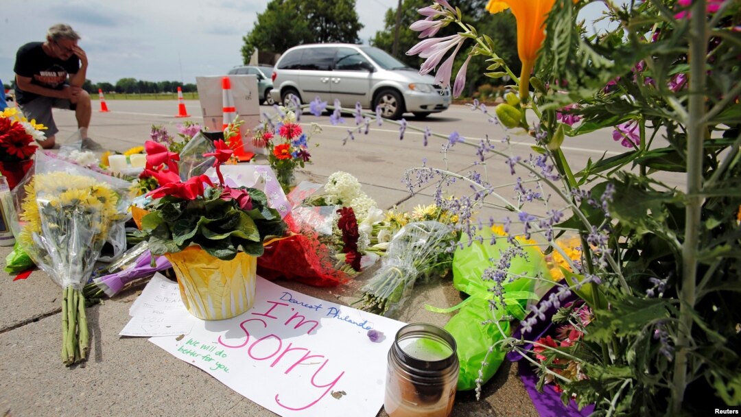A man kneels at a make-shift memorial at the site of the police shooting of Philando Castile in Falcon Heights, Minnesota, July 7, 2016.