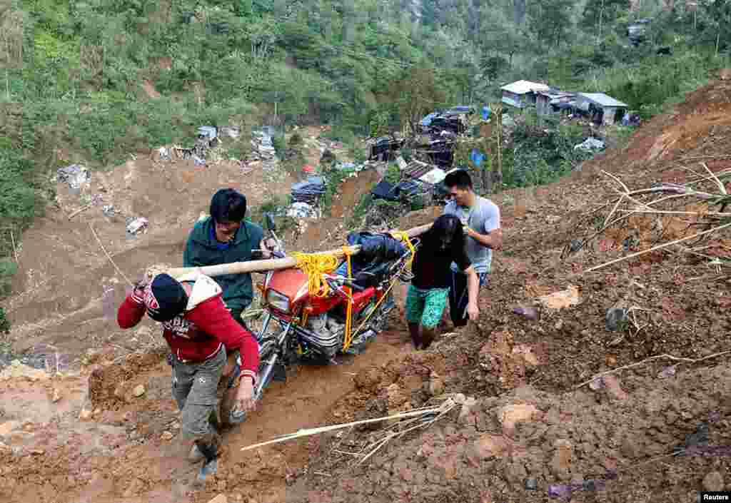 Residents carry a motorcycle on a road eroded by a landslide caused by Typhoon Mangkhut at a small-scale mining camp in Itogon, Benguet, in the Philippines.