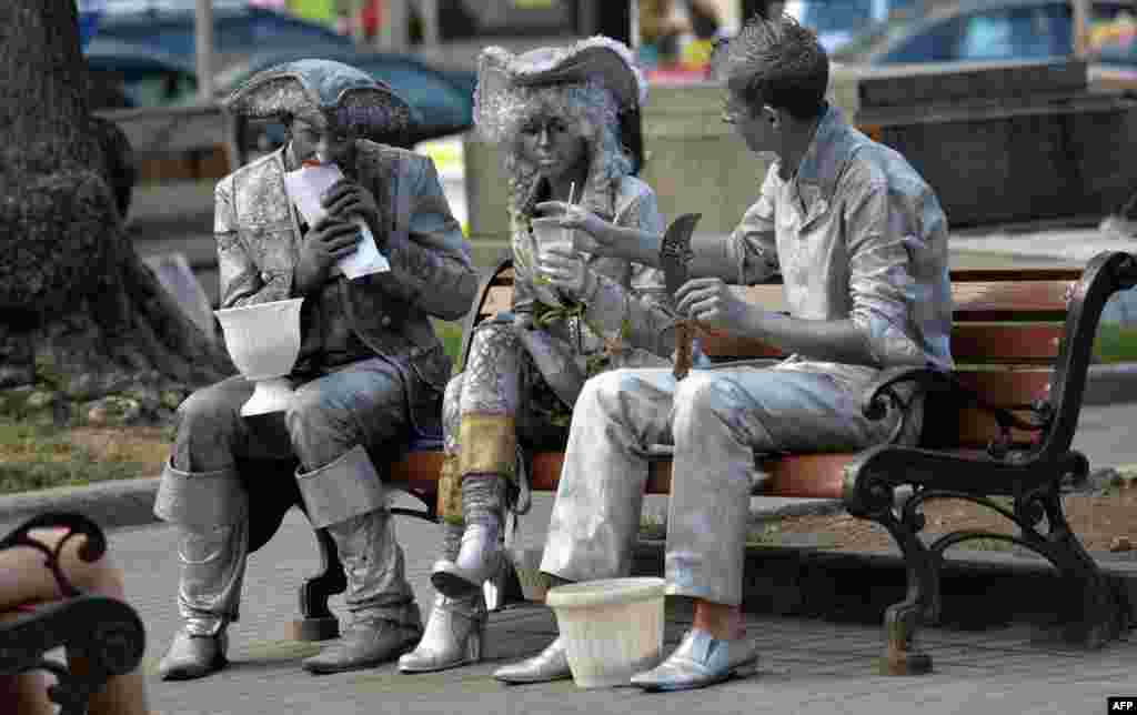 Street artists have a snack as they rest on a bench in the center of the Ukrainian capital Kyiv.