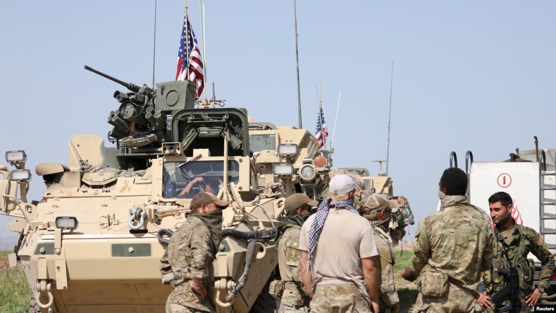 FILE - Kurdish fighters from the People's Protection Units (YPG) chat with members of U.S. forces in the town of Darbasiya next to the Turkish border, Syria, April 29, 2017.