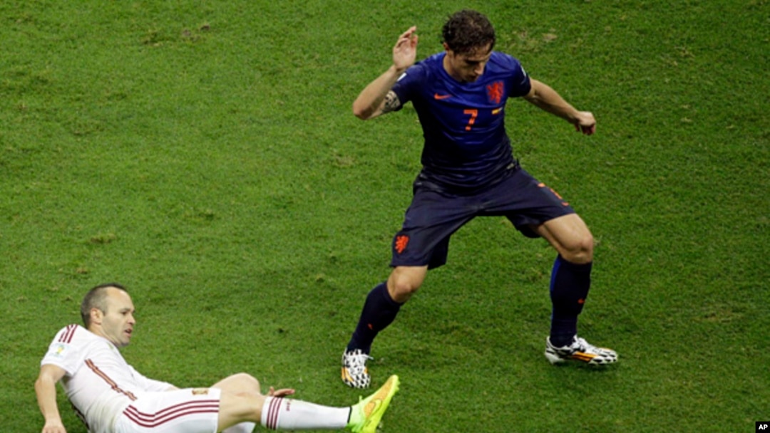Spain's Andres Iniesta tries to reach the ball against Netherlands' Daryl Janmaat during the group B World Cup soccer match between Spain and the Netherlands at the Arena Ponte Nova in Salvador, Brazil, June 13, 2014.