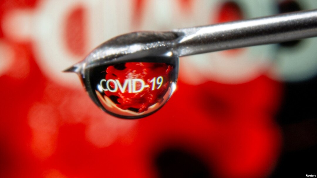 FILE - The word "COVID-19" is reflected in a drop on a syringe needle in this illustration