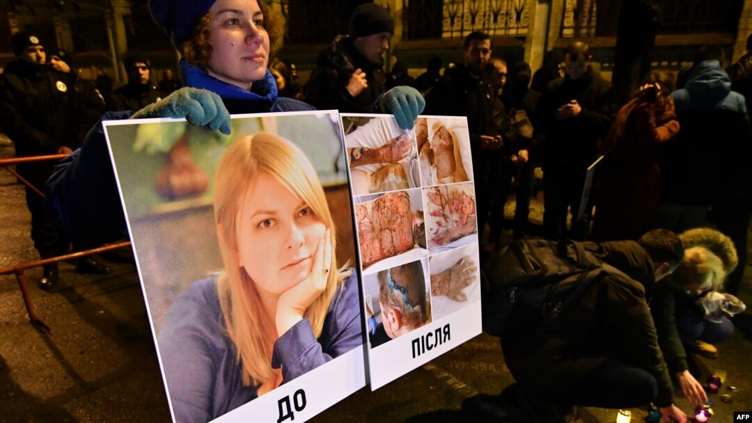 In this Feb. 4, 2019 photo, an activist holds a portrait of Kateryna Gandzyuk along with photos showing her traumas after the July 2018 acid attack that eventually killed the Ukrainian anti-corruption campaigner.
