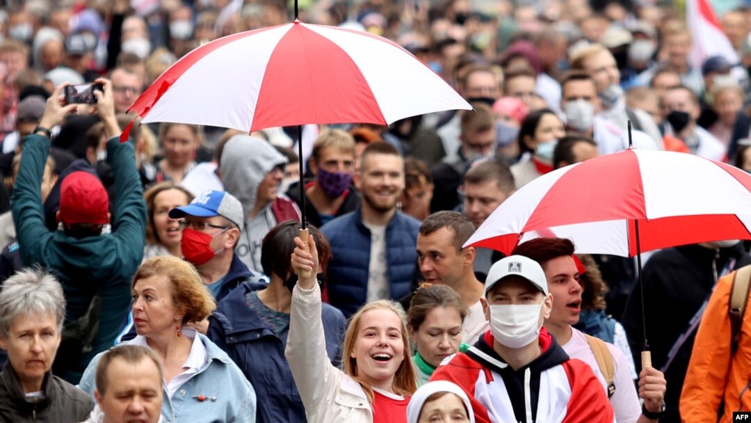 Opposition supporters carrying umbrellas in the colors of a former white-red-white fag of Belarus parade through the streets during a rally to protest against the presidential inauguration in Minsk, Sept. 27, 2020. 