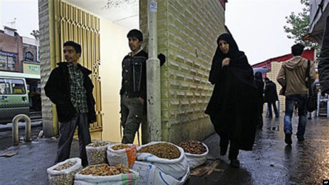 Pedestrians walk past vendor Amir Jamali, center, as he waits for customers after islamic leaders began cutting an estimated $100 billion a year in government subsidies for fuel and food, on a street in downtown Tehran, Iran, Nov 2010 (file photo)