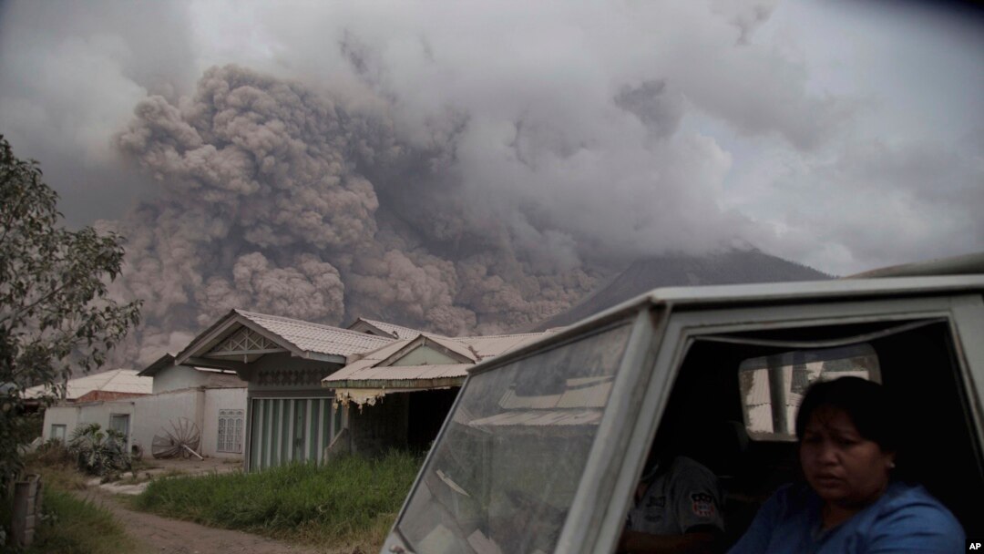 Residents ride in a truck as Mount Sinabung releases pyroclastic flows during its eruption in Karo, North Sumatra, Indonesia, Aug. 2, 2017.