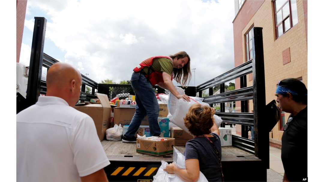 A member of the Red Cross unloads a truck of donations to waiting volunteers outside the Parthum School in Lawrence, Mass, Sept. 14, 2018.