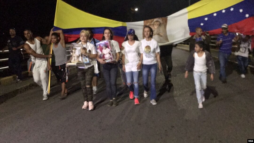 Luz Adriana Chalarca, in white shoes and carrying a figure of the Christ child, leads a prayer vigil on a bridge linking Cúcuta, Colombia, and northwest Venezuela. (C. Mendoza/VOA Spanish Service)