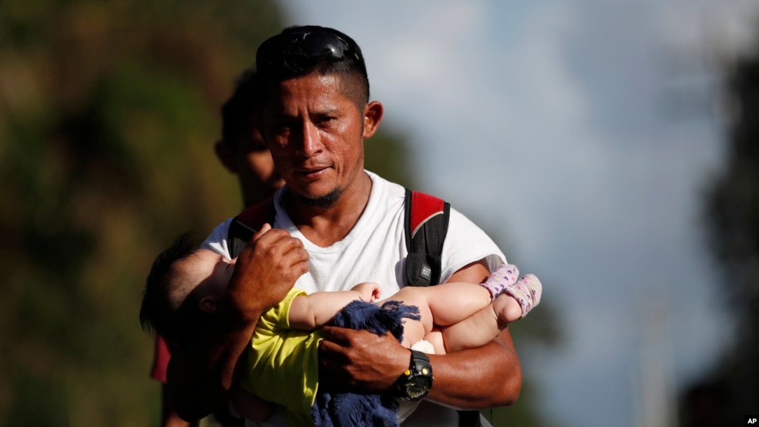 El migrante hondureño Selvin Hernández lleva a Mayra Irene, hija de otro migrante, en medio de una caravana que intenta llegar a Estados Unidos, cerca de El Cinchado, Guatemala.