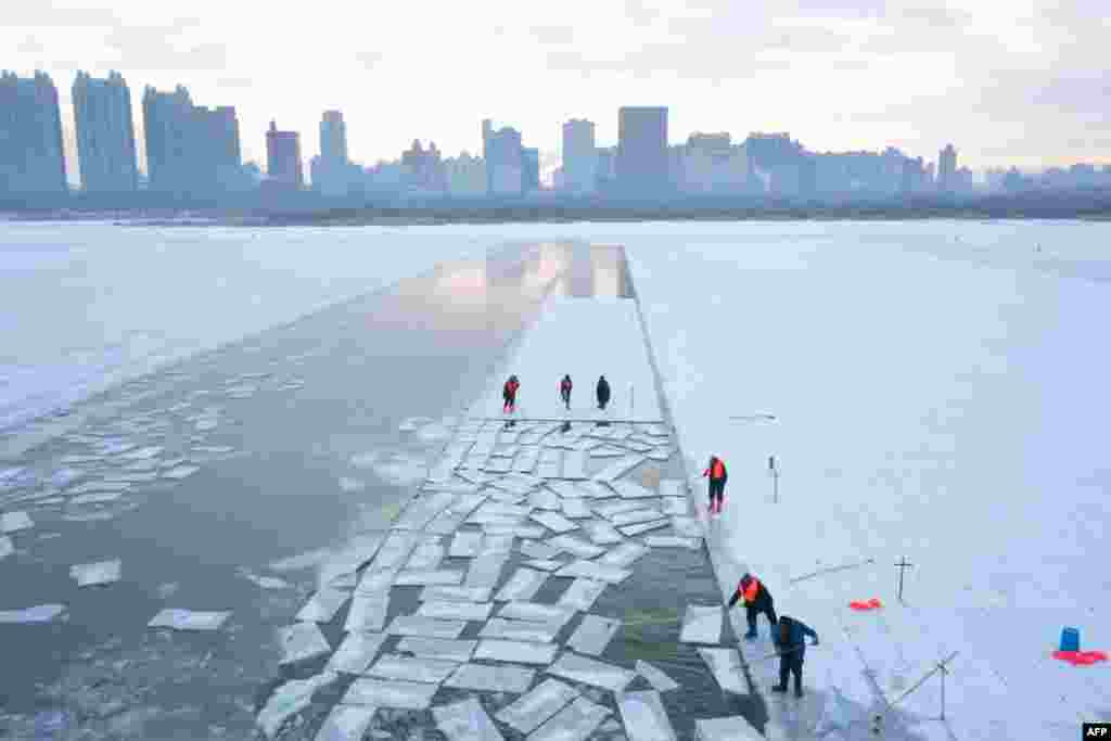 This aerial picture shows workers harvesting ice from the frozen Songhua river in preparation for the annual Harbin Ice and Snow World festival in Harbin, China's northeast Heilongjiang province, China, Dec. 17, 2024.