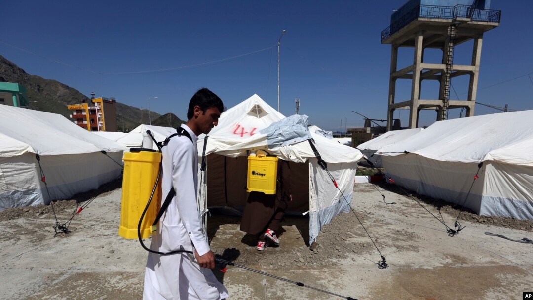 Afghan health workers in protective suits spray disinfectant on tents to help curb the spread of the coronavirus in the first quarantine camp for Afghan refugees crossing Torkham border from Pakistan to Afghanistan, April 4, 2020.