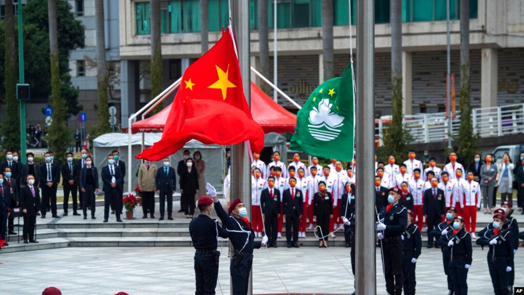 FILE - In this photo released by Xinhua News Agency, policemen perform a flag-raising ceremony in Macao, Dec. 20, 2021, marking the 22nd anniversary of the former Portuguese colony's handover to Chinese rule.