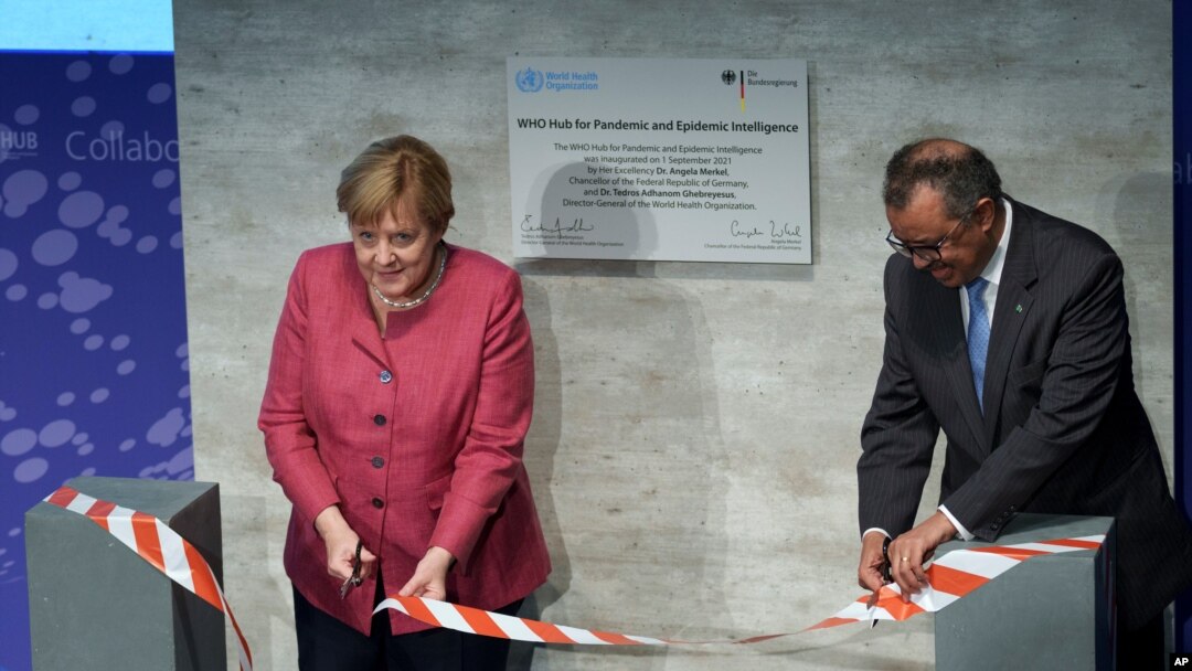World Health Organization chief Tedros Adhanom Ghebreyesus, right, and German Chancellor Angela Merkel cut the ceremonial ribbon at the inauguration of the "WHO Hub for Pandemic and Epidemic Intelligence,' in Berlin, Germany, Sept. 1, 2021. 