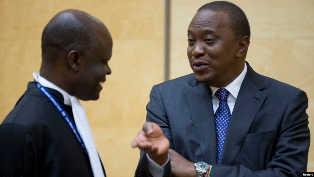Kenya's President Uhuru Kenyatta (R) speaks to a member of his defense team as he appears before the International Criminal Court at The Hague, Oct. 8, 2014.