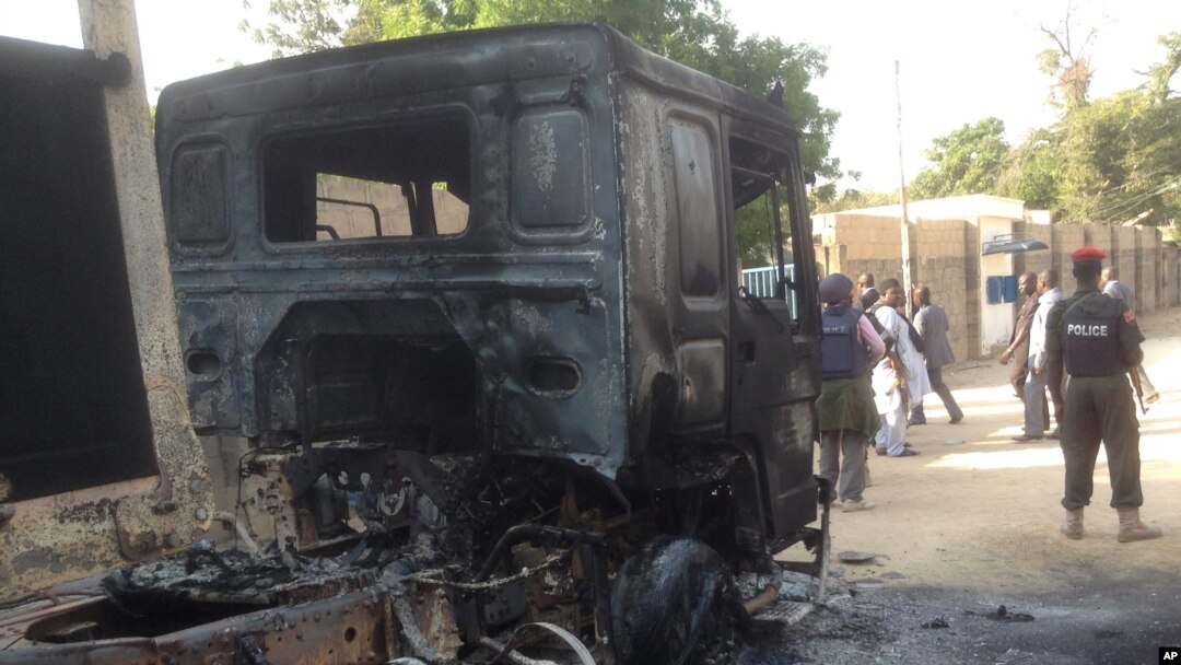 'Yansanda a jihar Barno suke gadi wata babbar mota da ake zargin 'yan Boko Haram suka kona.