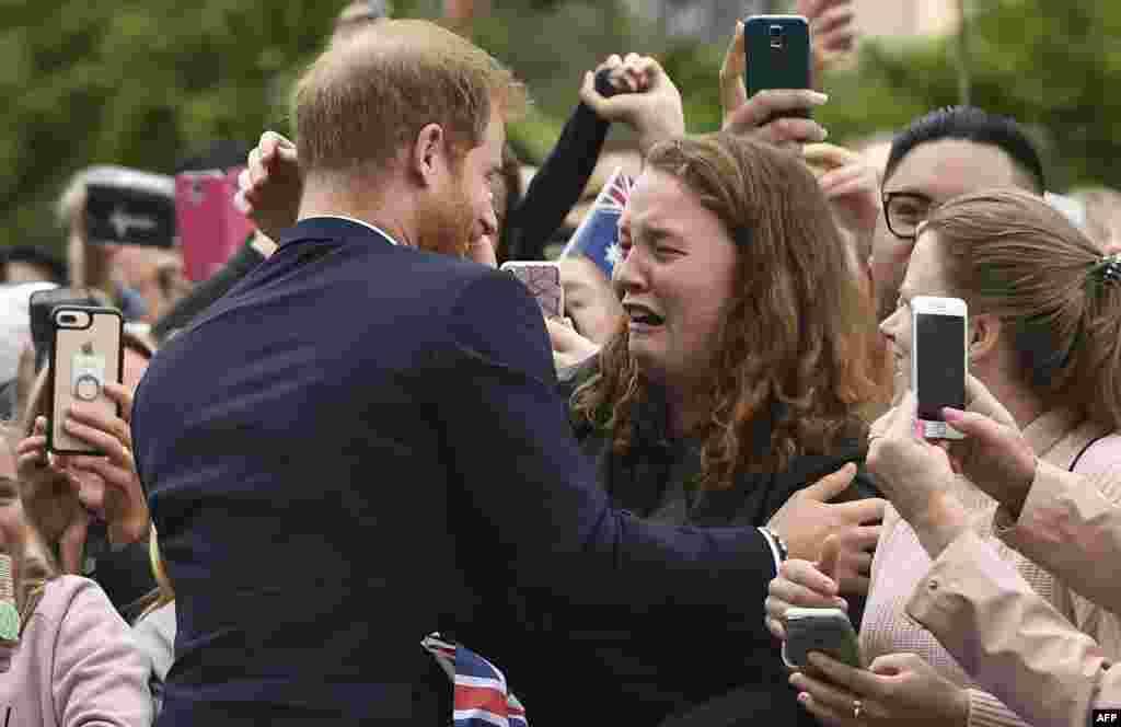 Britain's Prince Harry embraces India Brown during a public walk in Melbourne, Australia.