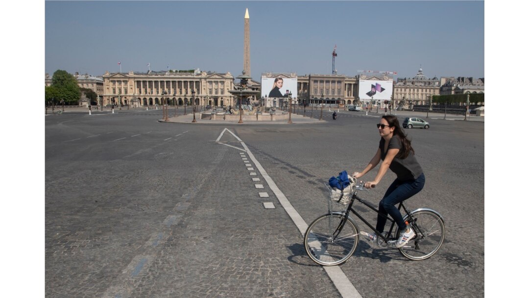 A woman crosses the Concorde square as she rides a bike during a nationwide confinement to counter the new coronavirus in Paris, Friday, April 10, 2020. (AP photo)