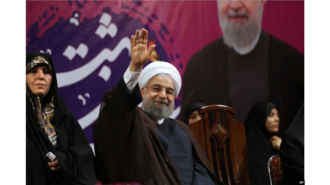 Iranian President Hassan Rouhani, center, waves to his supporters as he is accompanied by Vice President for Women and Family Affairs Shahindokht Molaverdi in a campaign rally for the May 19 presidential election in Tehran, Iran, May 9, 2017.