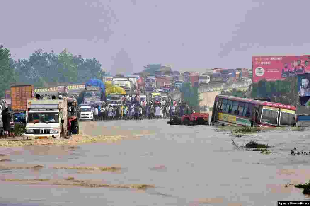 Commuters stand along a section of a flooded national highway after the Kosi River overflowed following heavy rains near Rampur in India's Uttar Pradesh state.