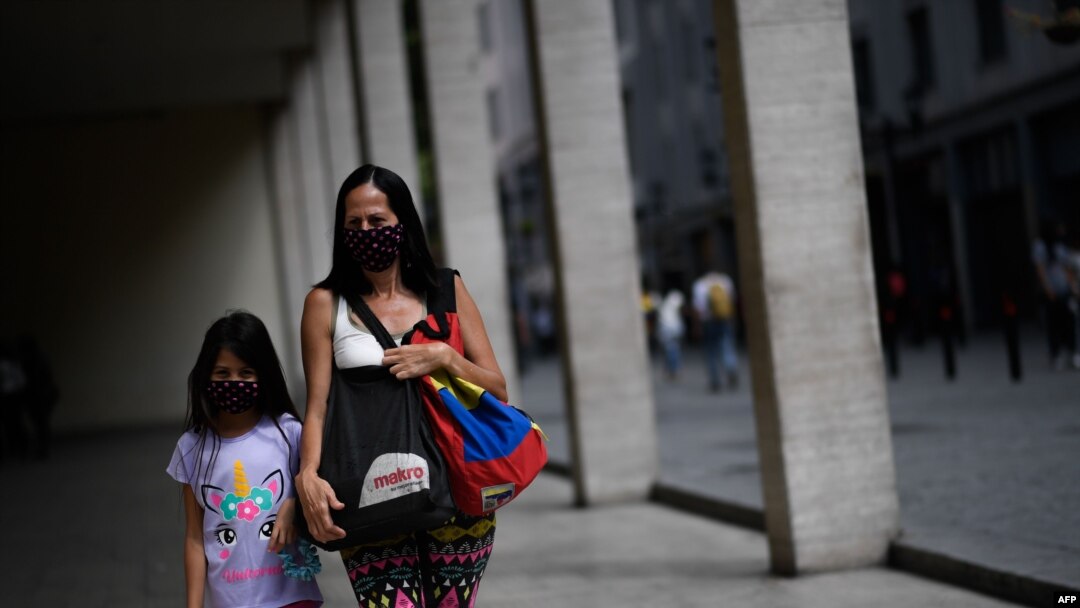 Una mujer y una niña usan tapabocas mientras caminan por el centro de Caracas después que el gobierno alivió el confinamiento nacional que impuso como medida preventiva contra la COVID-19.