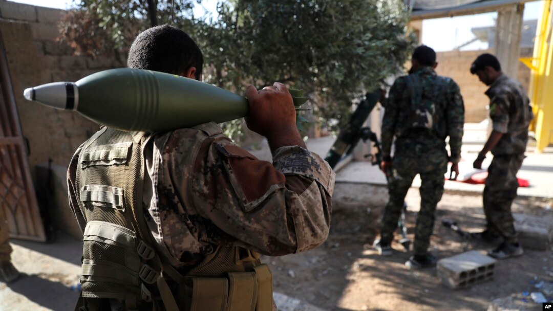 FILE - U.S.-backed Syrian Democratic Forces fighters, prepare to fire a mortar shell, at one of the front lines, in Raqqa city, northeast Syria, July 27, 2017.