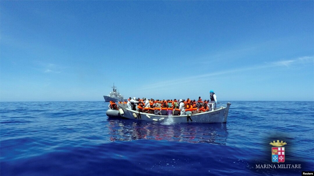 FILE Migrants sit in their boat during a rescue operation by Italian navy ship Grecale (unseen) off the coast of Sicily in this handout picture from the Italian Marina Militare, released May 6, 2016. 