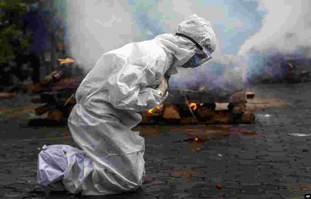 A woman breaks down as she prays before the cremation of a relative who died of COVID-19 in Gauhati, India. India on Friday crossed the grim milestone of more than 400,000 people lost to the coronavirus.