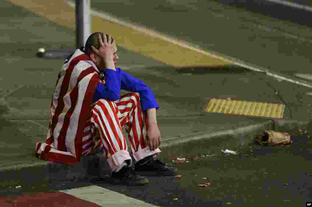 A man dressed in red-white-and-blue sits on the curb during a protest against President-elect Donald Trump, in Seattle's Capitol Hill neighborhood, Washington.