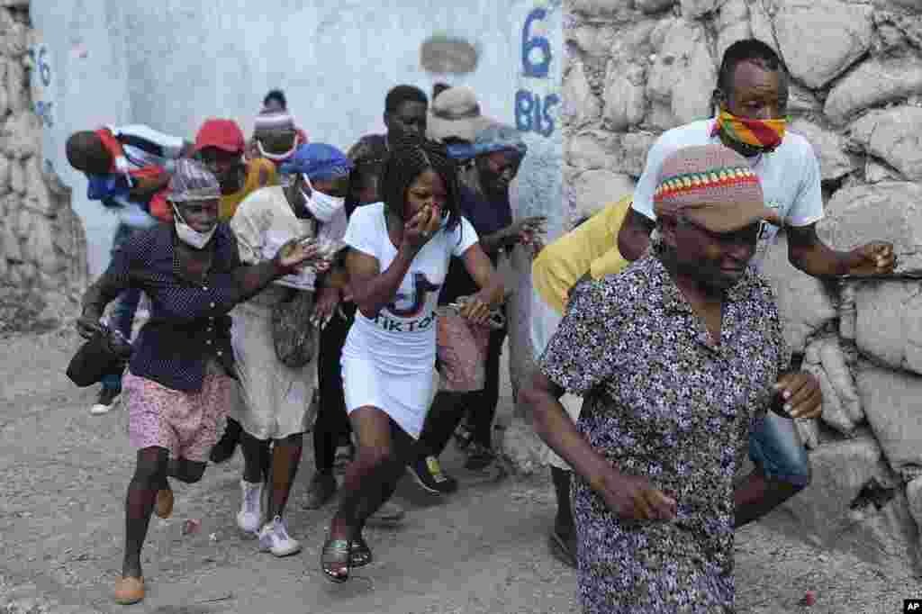 People who were marching to the prime ministers' residence, to demand justice for the assassination of Haitian President Jovenel Moise, run from tear gas fired by police in Port-au-Prince, Haiti.