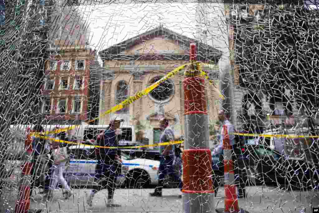New Yorkers pass a shattered storefront window on W. 23rd St. in Manhattan. The window was hit by shrapnel from the bomb that exploded across the street Saturday evening