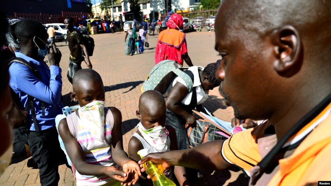 Mtu akiwapa watu vitakasa mikono kabla ya abiria hao kupanda basi akiwa ni hatua ya kudhibiti kuenea kwa virusi vya corona katika kituo cha mabasi cha zamani, Kampala, Uganda Machi 24, 2020. REUTERS/Abubaker Lubowa 