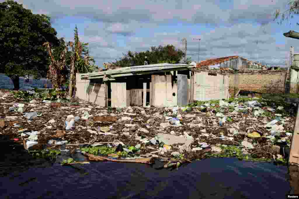 Houses are pictured partially submerged beside debris along a flooded street after heavy rains caused the Paraguay River to overflow, in a neighborhood on the outskirts of Asuncion, Paraguay, May 13, 2019.