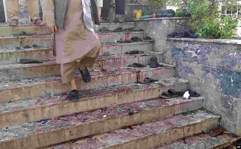 A man walks down blood-stained steps of a mosque following a bombing in Kunduz province, northern Afghanistan.