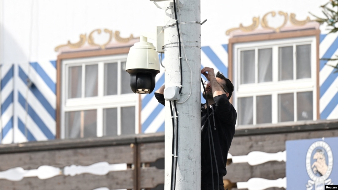 A worker installs a surveillance camera in front of a beer tent ahead of the 189th Oktoberfest, the world's largest beer festival, in Munich, Germany, Sept. 11, 2024.