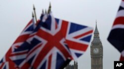 FILE - Union flags displayed on a tourist stall, backdropped by the Houses of Parliament and Elizabeth Tower containing the bell know as Big Ben, in London, Feb. 8, 2017. 