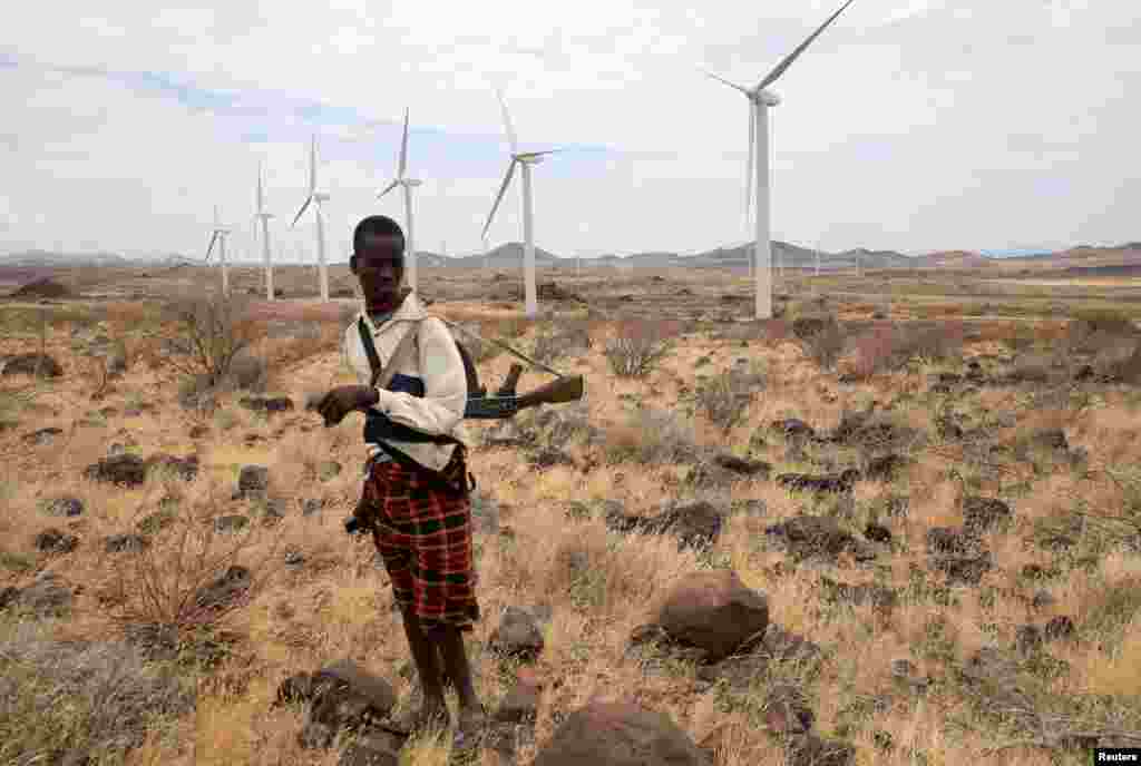 A Turkana herdboy carries his gun as he herds his goats near the power-generating wind turbines at the Lake Turkana Wind Power project (LTWP) in Loiyangalani district, Marsabit County, northern Kenya, Sept. 4, 2018.