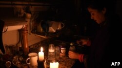 A woman prepares milk bottles using candles at her home in Montevideo, Uruguay, June 16, 2019, during a power cut. 