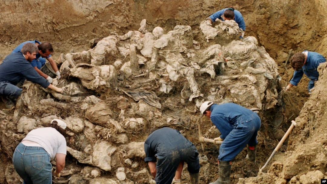 FILE - International war crimes tribunal investigators clear away soil and debris from dozens of Srebrenica victims buried in a mass grave near the village of Pilica, some 55 kms (32 miles) northeast of Tuzla, in 2006.