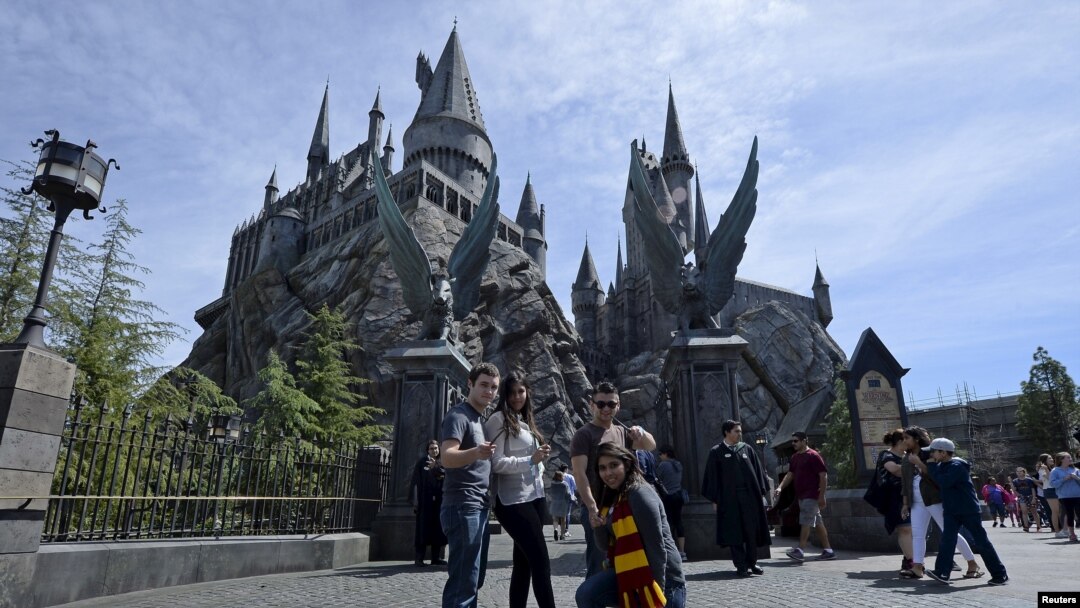 Guests pose before they enter Hogwarts School during a soft opening and media tour of "The Wizarding World of Harry Potter" theme park at the Universal Studios Hollywood in Los Angeles, California March 22, 2016. 