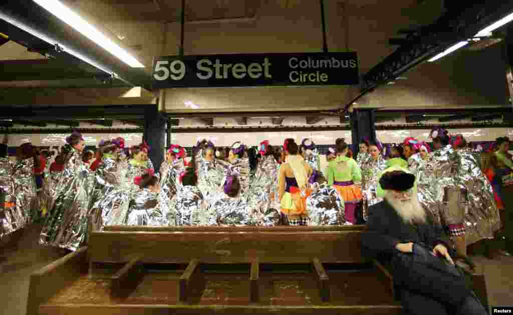 Performers of the 87th Macy's Thanksgiving Day Parade wait for a subway to take them to the start of the parade in New York.