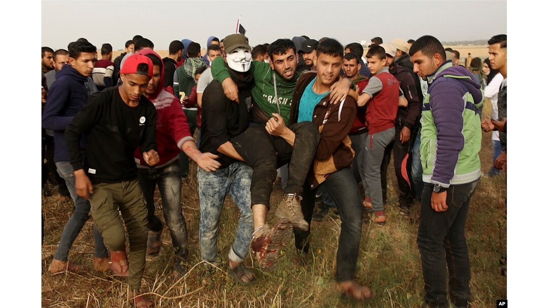 Palestinian protesters evacuate a wounded youth during clashes with Israeli troops along Gaza's border with Israel, east of Khan Younis, Gaza Strip, April 5, 2018. An Israeli airstrike in northern Gaza early Thursday killed a Palestinian, while a second man died from wounds sustained in last week's mass protest.