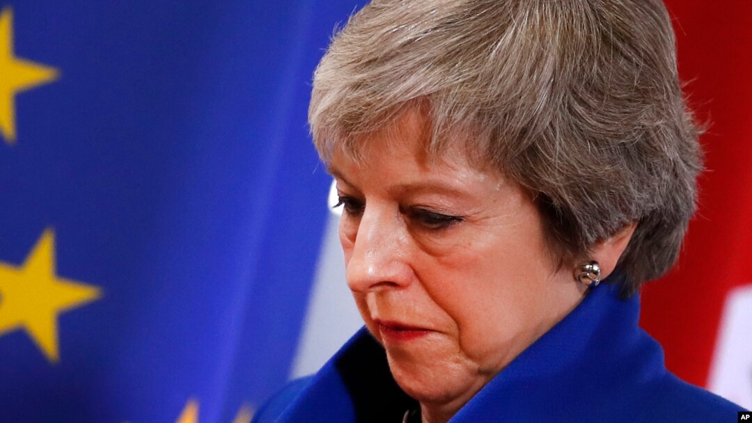 British Prime Minister Theresa May walks past the EU flag at the conclusion of an EU summit in Brussels, Nov. 25, 2018. European Union leaders gathered Sunday to seal an agreement on Britain's departure from the bloc next year.