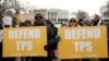 Demonstrators hold signs protesting the termination of Salvadorans' Temporary Protected Status