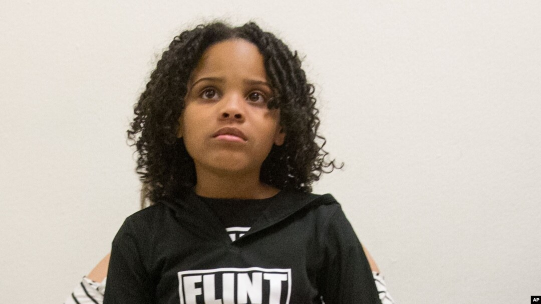 FILE - Mari Copeny, 8, of Flint, Mich. sits on the lap of her mother as they and other Flint residents and supporters wait outside the room where Michigan Gov. Rick Snyder and EPA Administrator Gina McCarthy testify before a House Oversight and Government Reform Committee hearing in Washington, March 17, 2016.