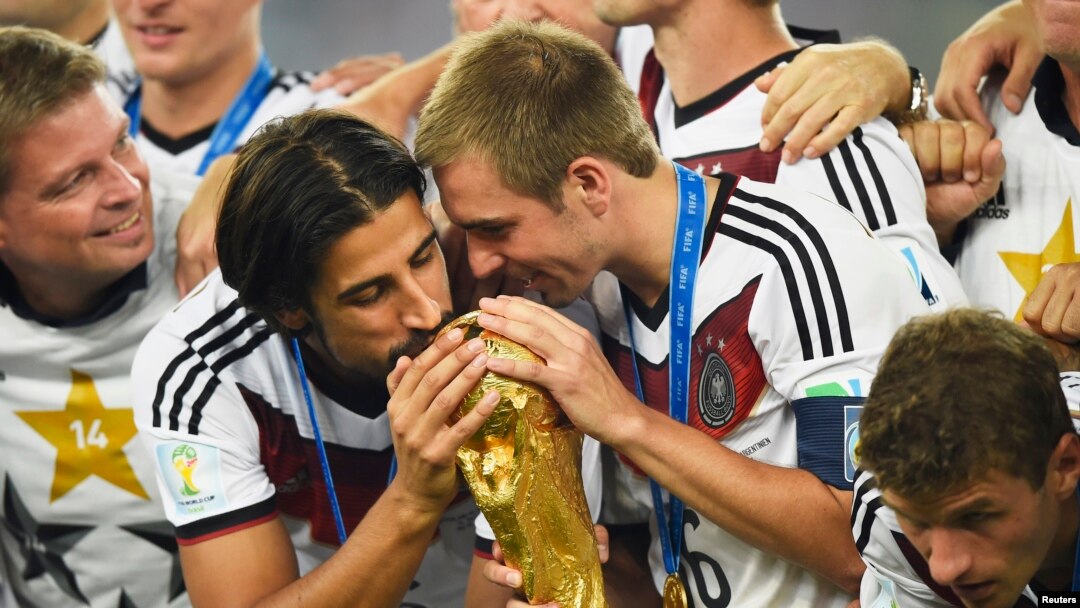 Germany's Sami Khedira (L) and Philipp Lahm (2nd R) kiss the World Cup trophy as they celebrate at the end of the 2014 World Cup final between Germany and Argentina at the Maracana stadium in Rio de Janeiro, July 13, 2014.