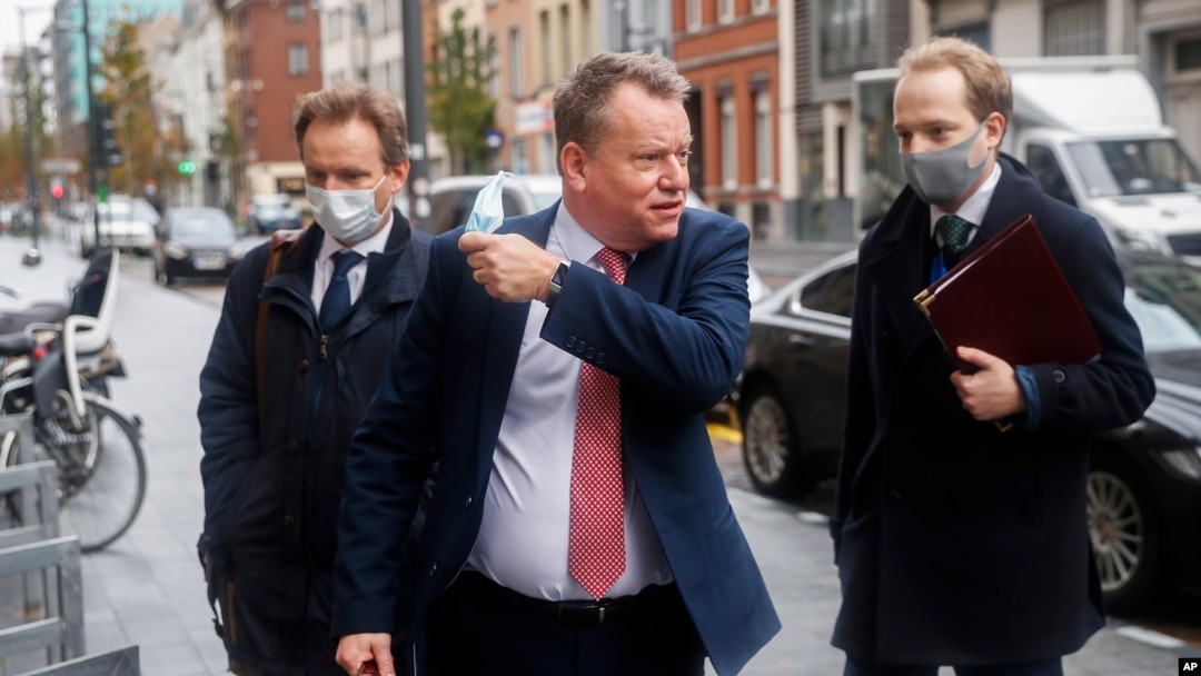 Britain's chief negotiator David Frost, center, removes his face mask to talk to the media as he arrives for Brexit talks with EU chief negotiator Michel Barnier in Brussels, Belgium, Nov. 16, 2020.